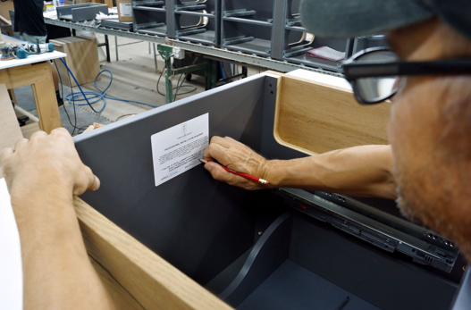A craftsman signing a finished vanity